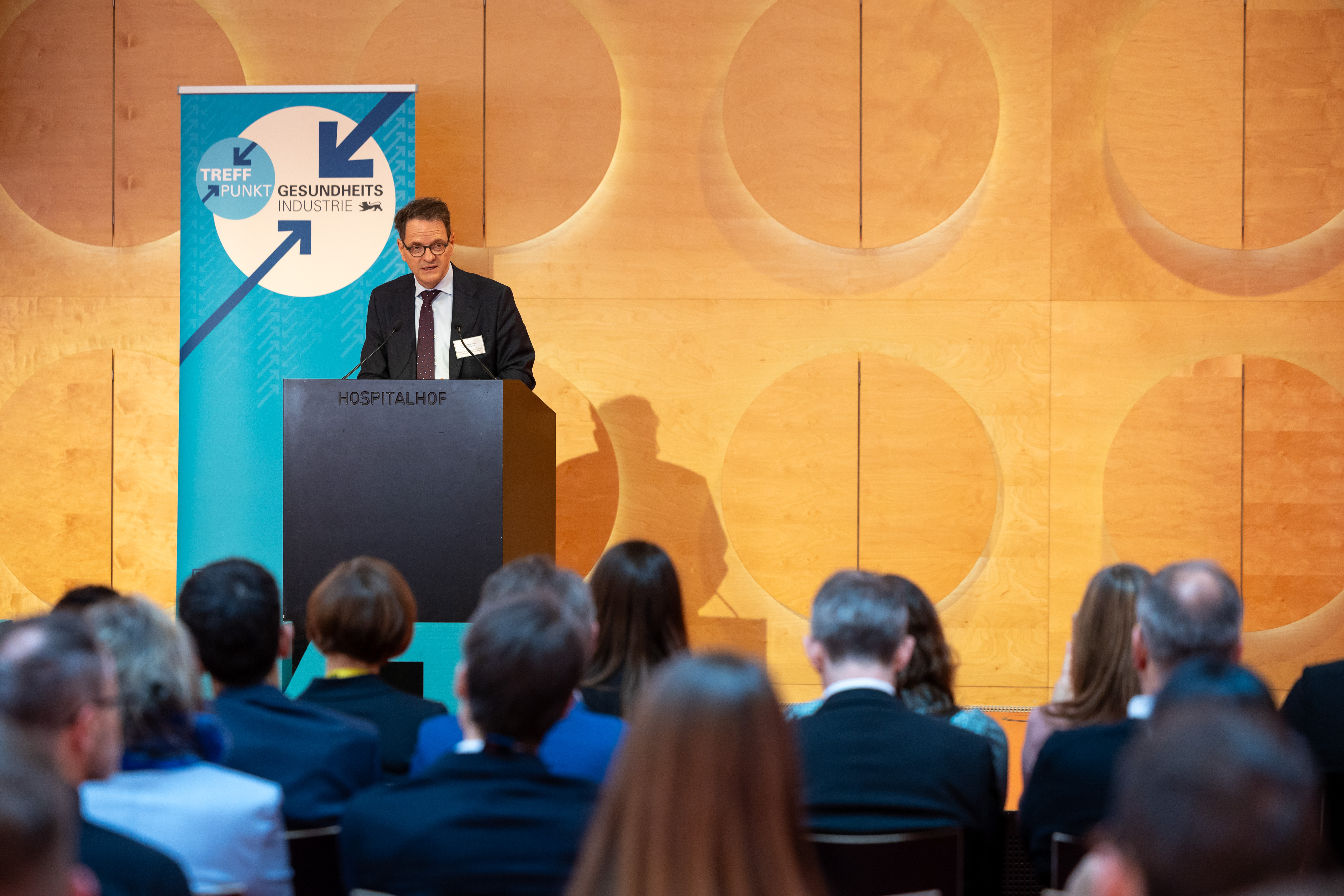 Ein Herr im Anzug spricht von der Bühne.