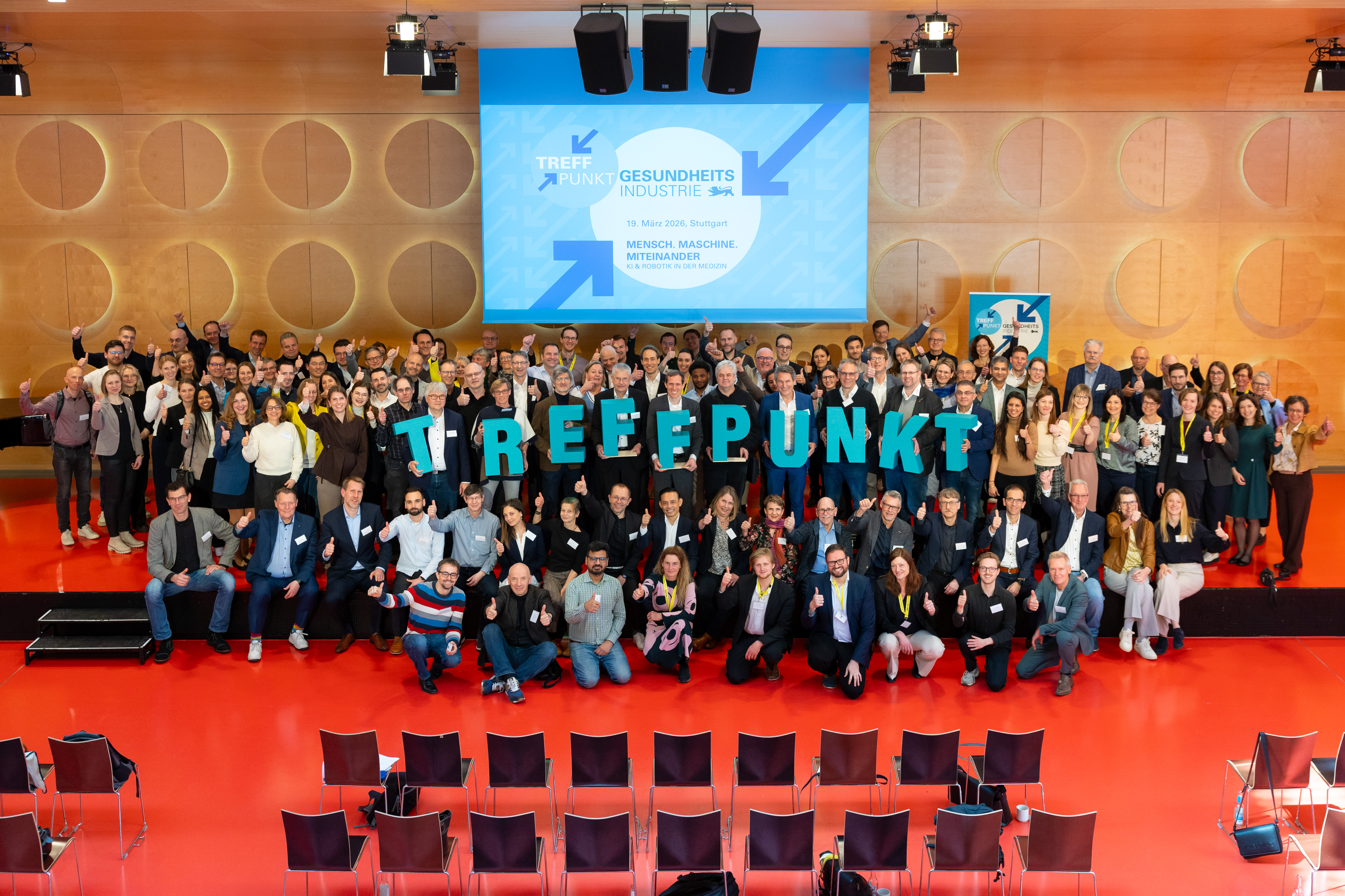 Eine große Personengruppe auf der Bühne für ein Gruppenbild. Sie halten die Buchstaben T-R-E-F-F-P-U-N-K-T nach oben.