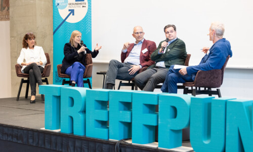 Podiumsdiskussion beim Treffpunkt Gesundheitsindustrie 2025 Fünf Personen sitzen auf einer Bühne und diskutieren miteinander, zwei halten Mikrofone. Im Vordergrund steht das Wort „TREFFPUNKT“ in großen Buchstaben.