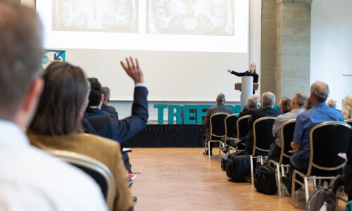 Fachvortrag mit Diskussion beim Treffpunkt Gesundheitsindustrie 2025 Person hält einen Vortrag vor Publikum und zeigt auf eine Präsentation mit medizinischen Bildern, eine Person im Publikum hebt die Hand für eine Frage.